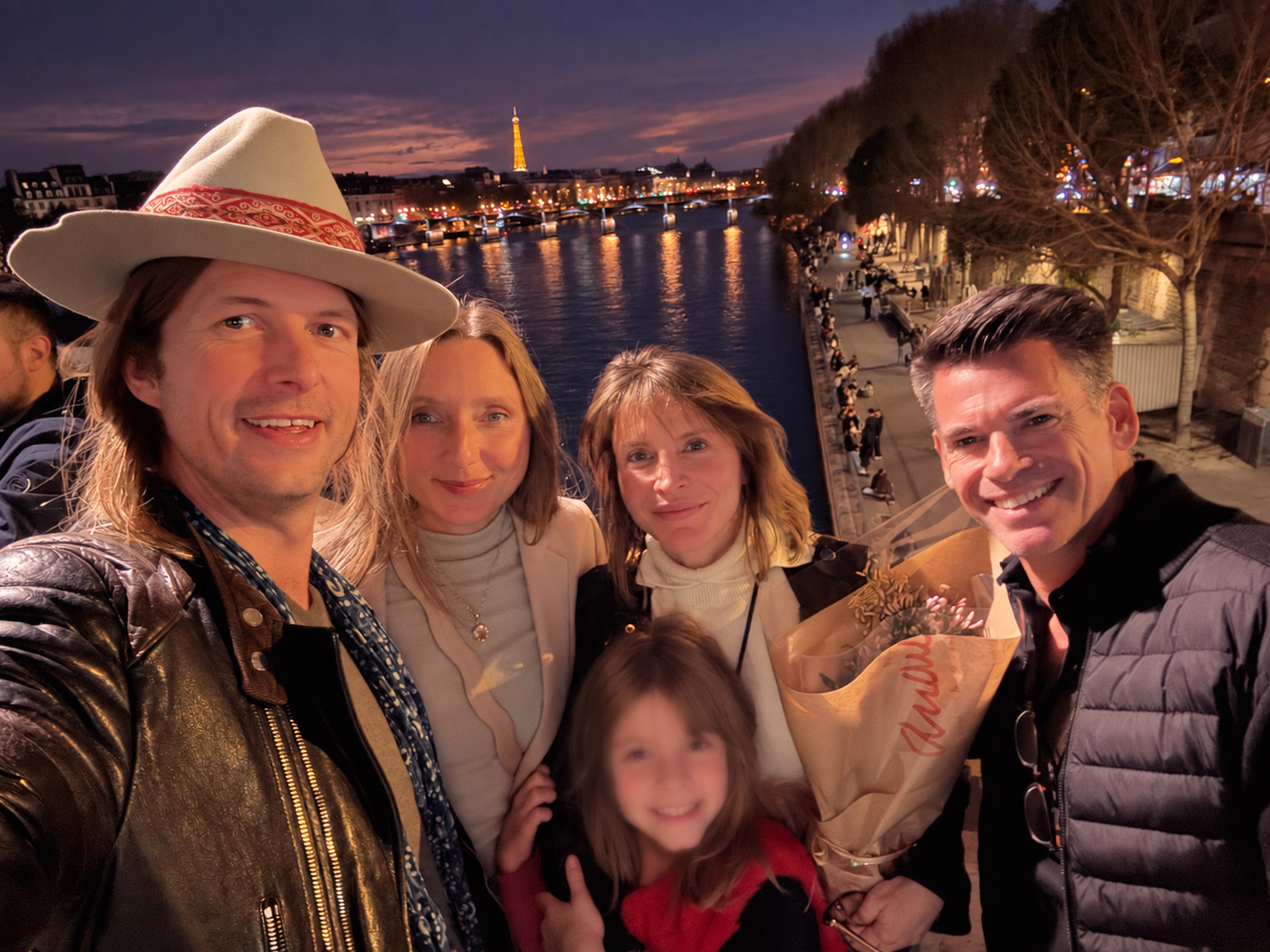 Lea with her former husband, his wife and their wider family together on a bridge in Paris at night.